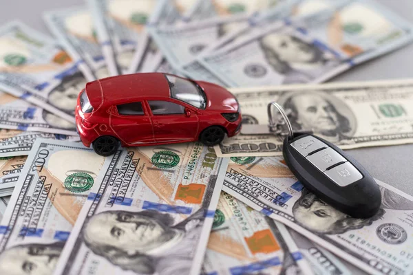 small toy car with real car keys lying dollar cash. Expensive gift. Sell or rent concept. High quality photo