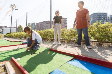 Aile bir yolcu gemisinde mini golf oynuyor. Çocuk tatillerde boş zamanlarında eğleniyor. Yüksek kalite fotoğraf