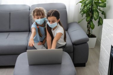 Yüz koruyucu maskeli genç liseli kızlar online eğitim sınıfını izliyorlar. Coronavirus veya Covid-19 tecrit eğitim kavramı