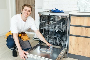 Bulaşık makinelerinin tamiri. Tamirci mutfakta bulaşık makinesini tamir ediyor..
