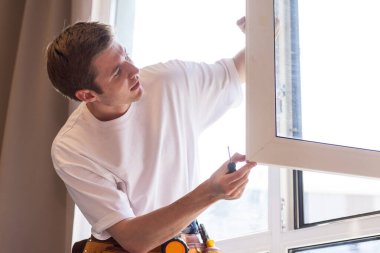 A repairman fixing windows in new apartment. clipart