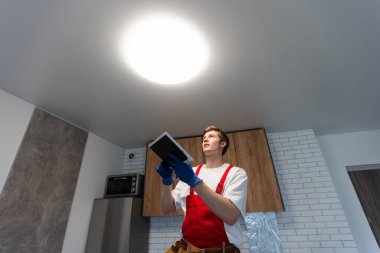 Üniformalı elektrikçi evin içine lamba yerleştiriyor. Metin için boşluk.