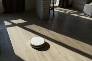 Robot süpürgesi güneşli bir günde parke zeminde..