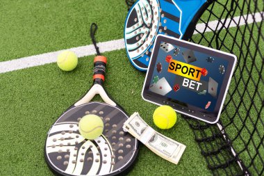 Tablet bilgisayar, para ve arka planda tenis roketi. Spor bahsi kavramı. Yüksek kalite fotoğraf