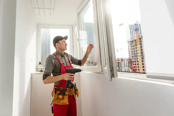 Construction worker repairing plastic window with screwdriver indoors. High quality photo