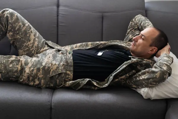 Young African American military man lying down on sofa and thinking of something at home. . High quality photo