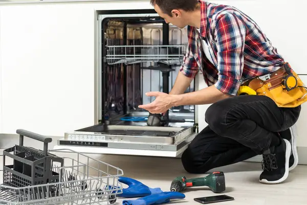 Man repairing a dishwasher with tools. High quality photo
