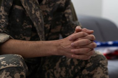 Askeri üniformalı bir adam pencerenin yanındaki sandalyede oturuyor. Konsept: Psikolog randevusunda bir asker, travma sonrası stres sendromu, zihinsel bozukluk, savaşın sonuçları..