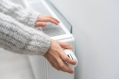 Çocuklar ellerini ısıtıcının yanında ısıtıyorlar. Isıtma mevsiminde benzin tasarrufu
