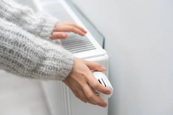 The childs hands warm their hands near the heating radiator. Saving gas in the heating season