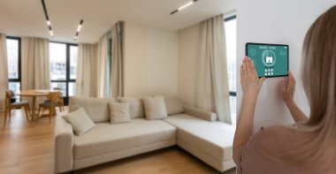 Oturma odasındaki duvara dijital dokunmatik ekran panelle evi kontrol etmek. Evdeki akıllı aygıtları yönetmek için akıllı ev ve mobil uygulama kavramı
