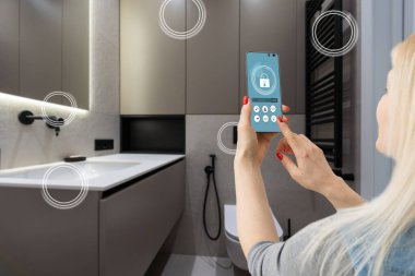 Akıllı ev teknolojisi, akıllı telefon uygulamasındaki IoT İnternet arayüzü modern apartman içindeki nesnelere bağlı ekran, uzaktan kumanda olarak kadın tutucu aygıtı.