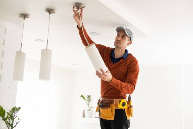 Apartmanın içine elektrik lambaları döşeyen elektrik işçisi. İnşaat dekorasyonu kavramı