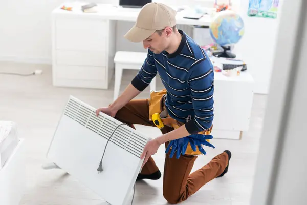 Modern electric heater on floor at home. the master repairs the electric heater