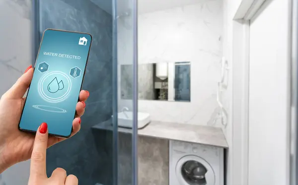 Hand holding smart phone with home control application with water detected, Smart home concept
