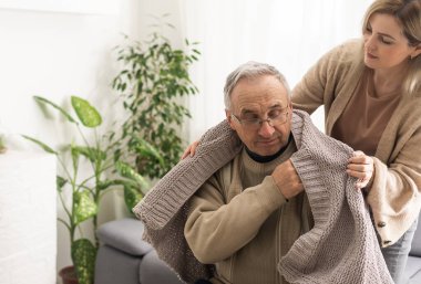 Hands of an elderly man holding the hand of a younger woman.