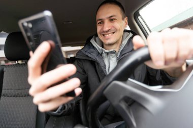 Kot gömlekli yakışıklı genç adam araba multimedya panelinde dokunmatik ekrana basıyor, radyo istasyonunu değiştiriyor. Yüksek kalite fotoğraf