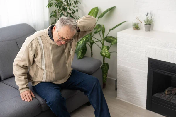 stock image Tired old man suffering from headache, massaging his temples. Strong migraine attack. An elderly man has a headache, massaging his temples.