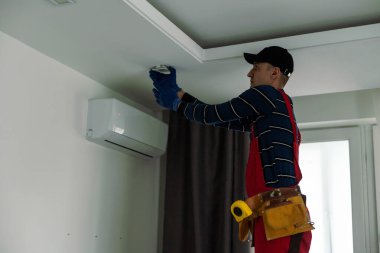 Bir elektrikçi tavana LED spot ışıkları kuruyor.