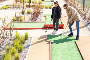 Family Time Playing Mini-Golf In The Summer. clipart