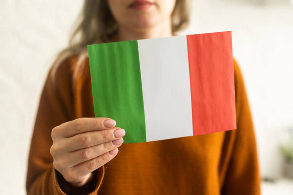Person holding a Italian flag on a white background.
