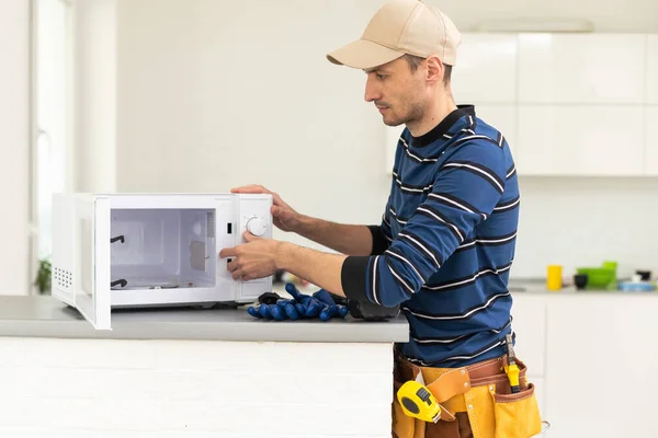 Young repairman fixing and repairing microwave oven