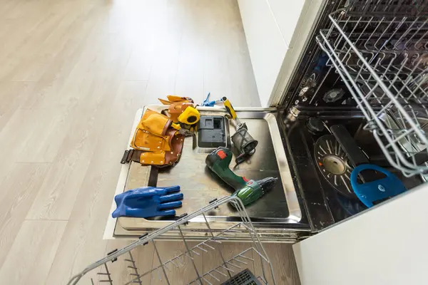 repair of a modern dishwasher with screwdrivers in the kitchen. High quality photo