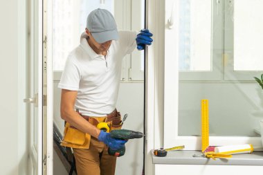 a repairman repairs, adjusts or installs metal-plastic windows in the apartment. glazing of balconies, loggias, verandas in house. production of double-glazed windows to individual sizes