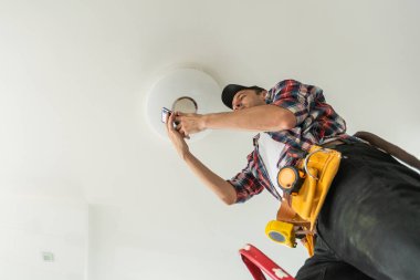 Elektrikçi tavan lambasına ampul takıyor. Yüksek kalite fotoğraf