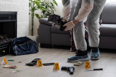 Criminological expert collecting evidence at the crime scene. High quality photo clipart