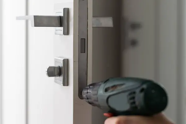 A handyman repair the door lock in the room. A locksmith install the new door lock in the room. High quality photo