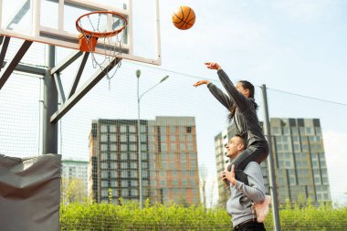 Baba ve kızı sokakta basketbol oynarken.