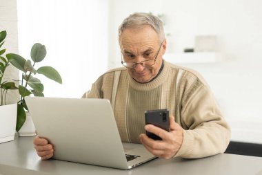 Pensive Senior Man Using Laptop Sitting At Home, Empty Space.