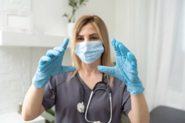 Yorgun kadın doktor. Koronavirüs. Koruyucu maskeli ve eldivenli genç bayan doktor parmak gösteriyor.