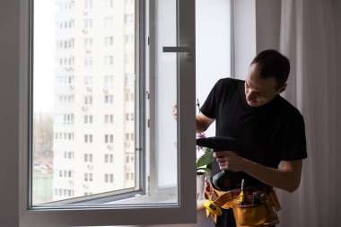 Tamirci pencere kolu takmak için kablosuz tornavida kullanıyor. Nitelikli işçi hizmetleri, ev onarımı ve yenileme. Yüksek kalite fotoğraf