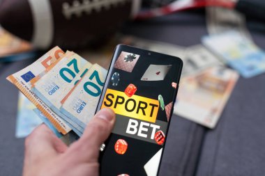 Smartphone with gambling mobile application, ball and money banknotes. Sport and betting concept. clipart