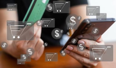 Çevrimiçi alışveriş ve e-ticaret kavramı. Alışveriş arabası simgesi olan dizüstü bilgisayar kullanan genç bir kadın, çevrimiçi mağazadan sipariş veren, internetten alışveriş yapan, klavyede yazı yazan sanal ekranda konsept kullanan bir kadın.