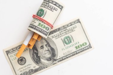 Pahalı bir alışkanlık ve sigara içilmez konsepti. Beyaz arka planda sigara bulunan dolar banknotları. Yüksek kalite fotoğraf