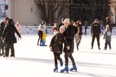 Action shot of beautiful woman teaching her daughter how to ice skate.
