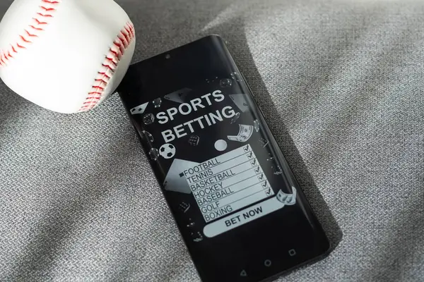 Business and sport concept. Ball and smartphone with bet application on dollar bills and keyboard. High quality photo
