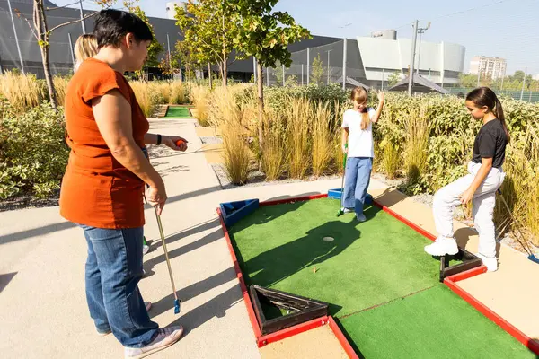 stock image Mother and her little daughter practicing to hit the ball at the course. High quality photo