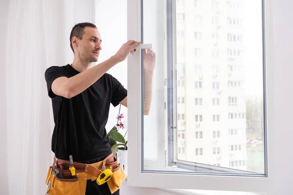 Stock image Handyman using a cordless screwdriver to install a window handle. Qualified worker services, home repair and renovation. High quality photo