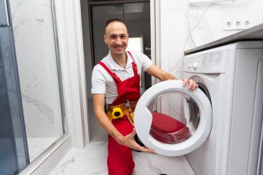 İç kısımda profesyonel bir tamirci çamaşır makinesini tamir ediyor. Yüksek kalite fotoğraf