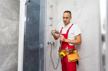 Duş kabininde çalışan profesyonel bir tamirci. Yüksek kalite fotoğraf