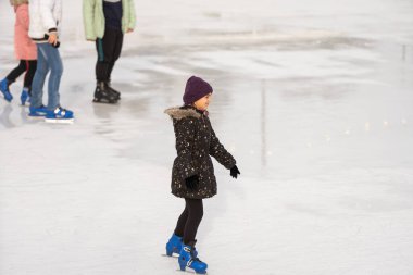 teenage girl ice skating on rink outdoors.