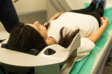 Bir kadın tomografi masasında yatıyor. Kadın, modern bir hastanede bilgisayarlı tomografi muayenesinden geçiyor..
