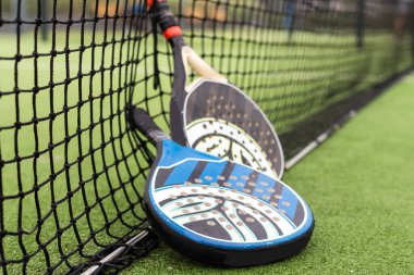 Mavi padel raketi ve sarı toplar güneşli bir günde kaleye yakın bir yere konur. Yüksek kalite fotoğraf