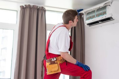 Yeni klima ünitesini bağlayan işçi..