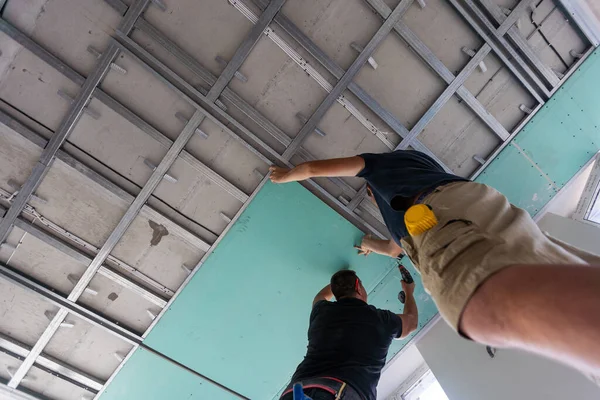 İşçiler paneli tavan çerçevesine yerleştiriyorlar. Yüksek kalite fotoğraf