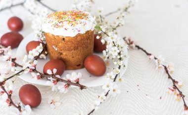 Paskalya kompozisyonu. Çiçekli bir kayısı dalı, boyanmış yumurtalar ve şeker parçacıklarıyla süslenmiş paskalya pastası..